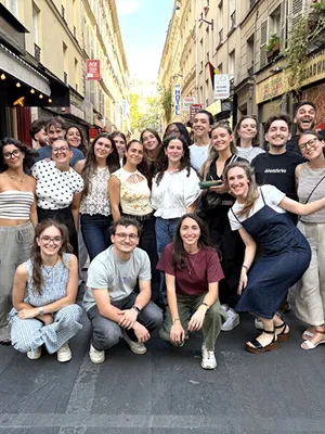 The Vente-unique team, about twenty people posing together in a narrow Paris street lined with shop fronts